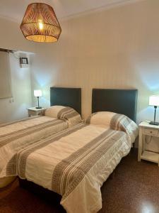 two beds in a room with two lamps on tables at Natullins Apartment in Ezeiza