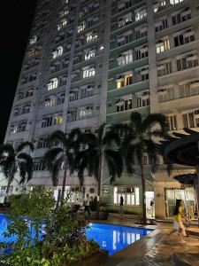 a large building with palm trees in front of it at Sweet Stay at Manila in Manila