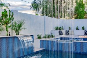 a swimming pool with a waterfall in a garden at The Carlisle Luxe Villa in Scottsdale
