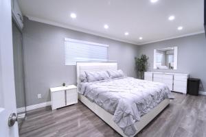 a white bedroom with a bed and a mirror at Modern LA Home - King Bed, Outdoor Living, Firepit in Los Angeles