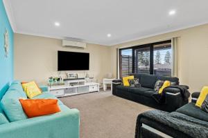 a living room with two couches and a flat screen tv at Seaside Living, Family Style! in The Entrance