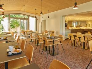a restaurant with tables and chairs and a kitchen at Hôtel REVOTEL Nancy Centre Gare et Congrès in Nancy
