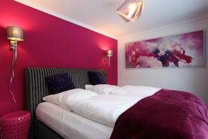 a bedroom with purple walls and a bed with white sheets at Kunst Pension Frahm in Basthorst