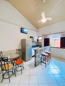 Una cocina con mesa y sillas y un refrigerador. en Vilamaruá Chalé próximo da praia do Perequê, en Ilhabela