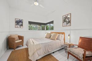 a bedroom with a bed and a chair and windows at Driftwood Beach House - A Cosy Coastal Cottage in Aldinga Beach