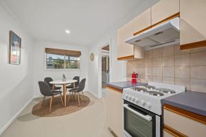 a kitchen with a stove and a table with chairs at Driftwood Beach House - A Cosy Coastal Cottage in Aldinga Beach +25 photos