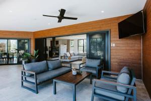sala de estar con sofá, sillas y ventilador de techo en The Wine Manor - Lavish Poolside Living, en Mudgee