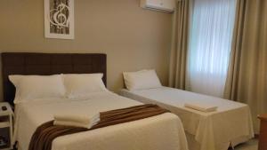 a hotel room with two beds and a window at Suítes Garden in Pomerode