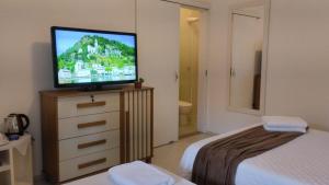 a bedroom with a television on top of a dresser at Suítes Garden in Pomerode