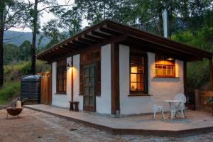 Cob Cabin - Sacred Earth Farm في Pumpenbill: منزل صغير أمامه طاولة وكراسي