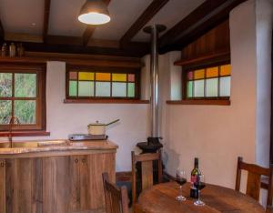 Cob Cabin - Sacred Earth Farm في Pumpenbill: مطبخ مع طاولة مع كؤوس للنبيذ عليه