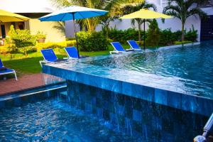a swimming pool with blue chairs and umbrellas at Eat Work and Sleep in Somone