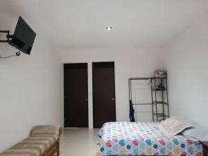a bedroom with a bed and a tv and a couch at Casa Vacacional in Uruapan del Progreso
