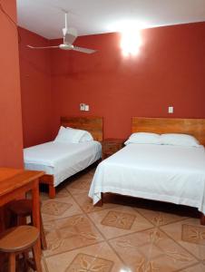 two beds in a room with red walls at Hospedaje casa Yuca in Valladolid