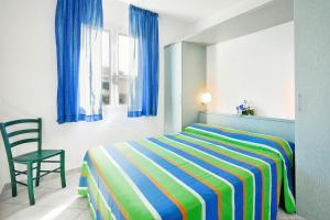 a bedroom with a bed with a chair and blue curtains at Villa in Cecina Mare near Sandy Beaches in Marina di Cecina