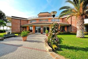 a large brick building with a palm tree and a courtyard at Villa in Cecina Mare near Sandy Beaches in Marina di Cecina