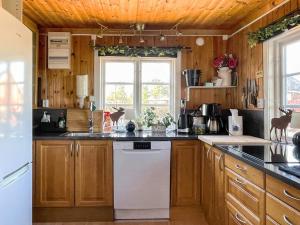 a kitchen with wooden cabinets and a white dishwasher at 4 person holiday home in BÄCKEFORS in Bäckefors