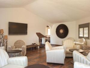 a living room with white chairs and a flat screen tv at Hôtel Ambassador Palombaggia in Porto-Vecchio