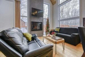 a living room with a leather couch and a fireplace at Havre de Paix in Saint-Rémi-dʼAmherst