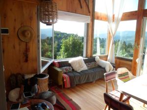 sala de estar con sofá y ventana grande en Un Viston Modern Mountain Home en San Martín de los Andes