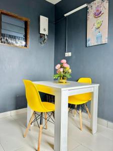 una mesa blanca con sillas amarillas y un jarrón de flores en Laetitia Belle Vue, en Abiyán
