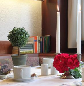 a table with two candles and red flowers on it at Hotel Grüner Baum in Stollberg