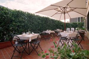 eine Terrasse mit Tischen, Stühlen und einem Sonnenschirm in der Unterkunft Bed and Breakfast San Francesco in Buti