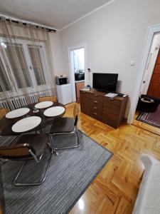 a living room with a table and chairs and a television at Apartman Dream M Zaječar in Zaječar