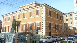 un gran edificio de ladrillo con coches estacionados frente a él en Hotel della Vittoria, en Ancona