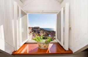 una ventana abierta con un jarrón sobre una mesa de madera en Rooms Lavanda&Ruzmarin, en Dubrovnik