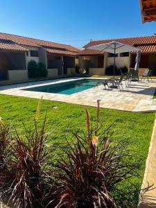 a backyard with a swimming pool and a lawn with plants at Pousada Vila da Mata - Canastra in São João Batista do Glória