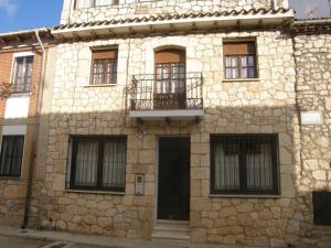 Edificio de piedra con puerta y balcón en Casa Rural Baco, en Baños de Valdearados