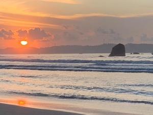 una puesta de sol en la playa con una roca en el agua en Double G Motel, en Weligama