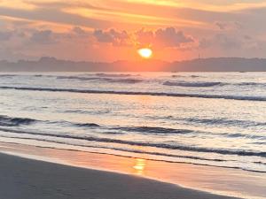 una puesta de sol en una playa con el océano en Double G Motel, en Weligama