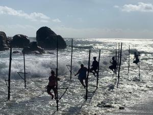 Un grupo de personas saltando al agua en la playa. en Double G Motel, en Weligama