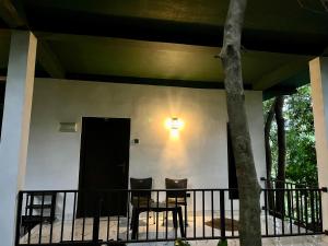 a porch with two chairs and a black door at Green House Resort in Sigiriya