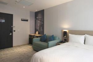 una camera d'albergo con letto e sedia blu di Tango Inn Taipei Kaifong a Taipei