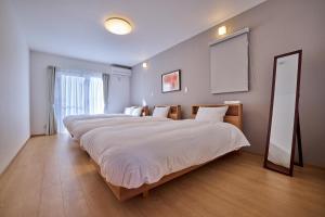 una camera da letto con due letti e uno specchio di COZY FUJI VIEW Stay a Fujikawaguchiko