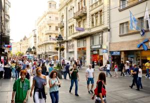 uma multidão de pessoas andando por uma rua movimentada da cidade em Eden Garden Suites em Belgrado