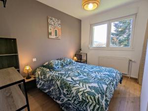 ein Schlafzimmer mit einem Bett mit einer blau-weißen Bettdecke in der Unterkunft Séjour détente en campagne avec spa et activités famille - FR-1-589-757 in Fraize