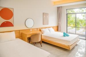a room with two beds and a desk and a mirror at The Vista Châu Đốc Hotel in Chau Doc