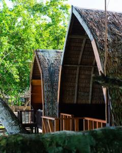 a building with a thatched roof and a tree at Koridek Homestay in Friwin