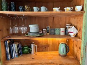 a wooden shelf with plates and cups and books at The Venus room at Glendower Homestead in Greytown
