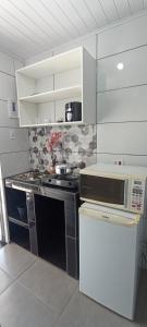 a small kitchen with a stove and a microwave at Vila Foz HOSTEL AP8 Apartamento completo de casal com ar condicionado, garagem fechada e lavanderia, Temos Uber e guia turístico para indicar, nosso apartamento é o melhor custo benefício de Foz do Iguaçu in Foz do Iguaçu