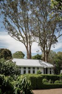 una casa blanca con árboles delante en The Merribee, Villa Botanica, en Numba