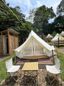 a tent with two chairs and a wooden table at Bunihayu Forest in Peuteuy