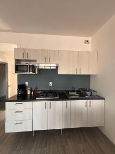 a kitchen with white cabinets and a black counter top at KAVA lofts in El Pueblito +29 photos