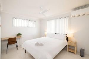 a white bedroom with a bed and a desk at Smart Suites Self Check-in Apartments - W Freney in Brisbane +59 photos