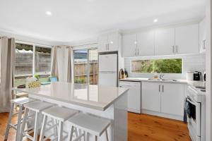 una cucina con armadi bianchi e piano di lavoro bianco di 2 Russell a Anglesea