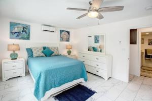 a white bedroom with a blue bed and a ceiling fan at Beautiful Ocean Views Amazing Sunsets three pool! in Nazareth +27 photos